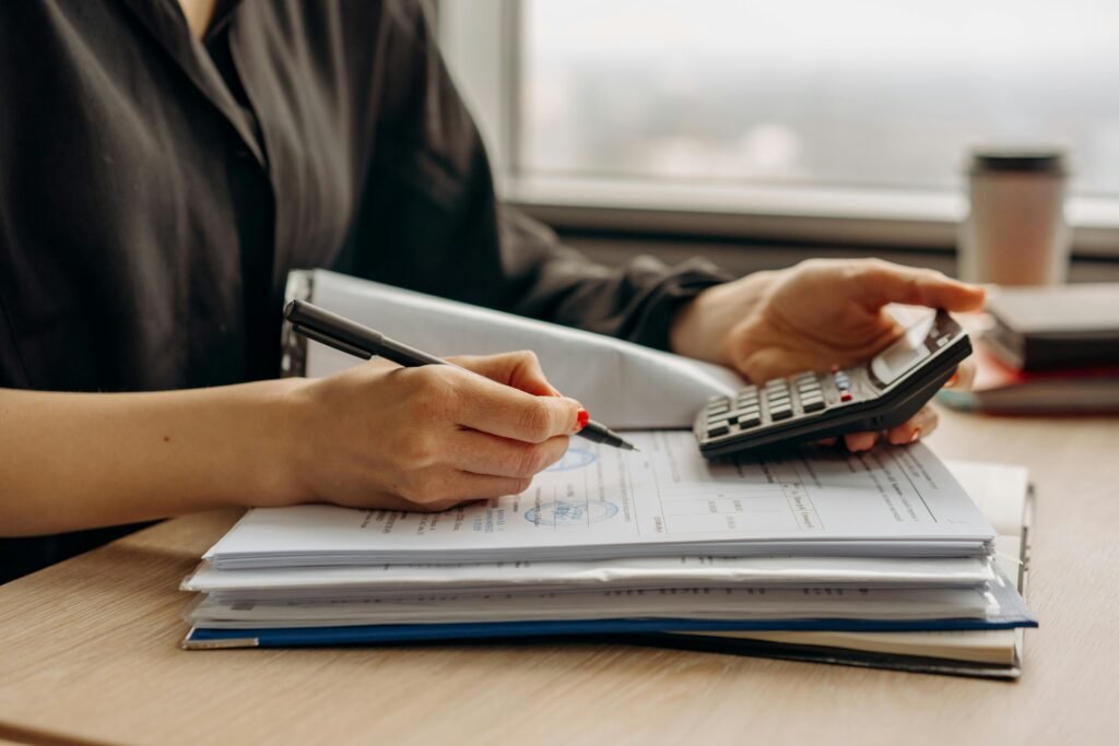 pexels-photo-8297031-8297031 Close-up of person using a calculator with financial documents in an office.